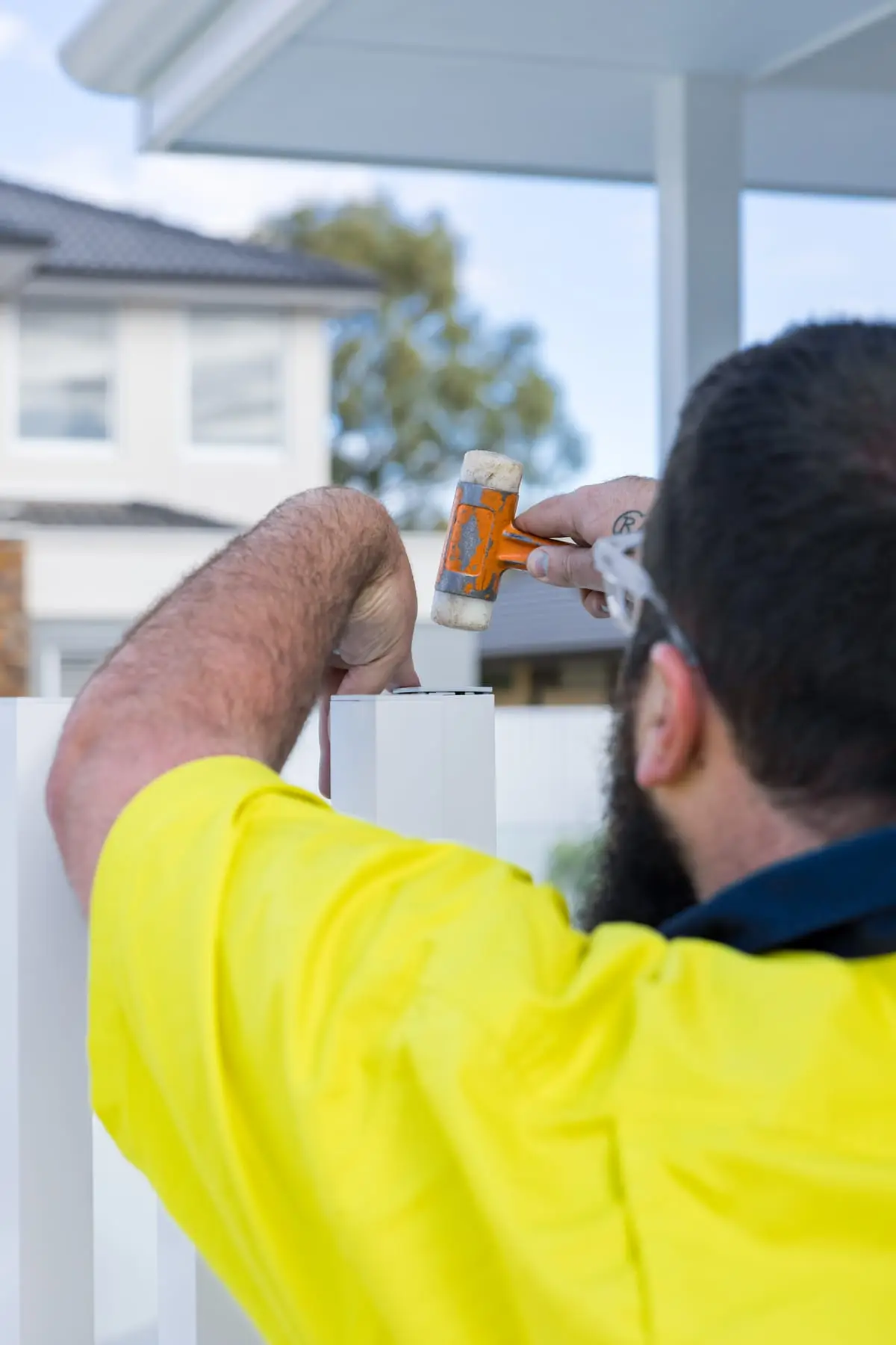 An installer tapping an end cap onto a white aluminium batten with a soft-faced mallet