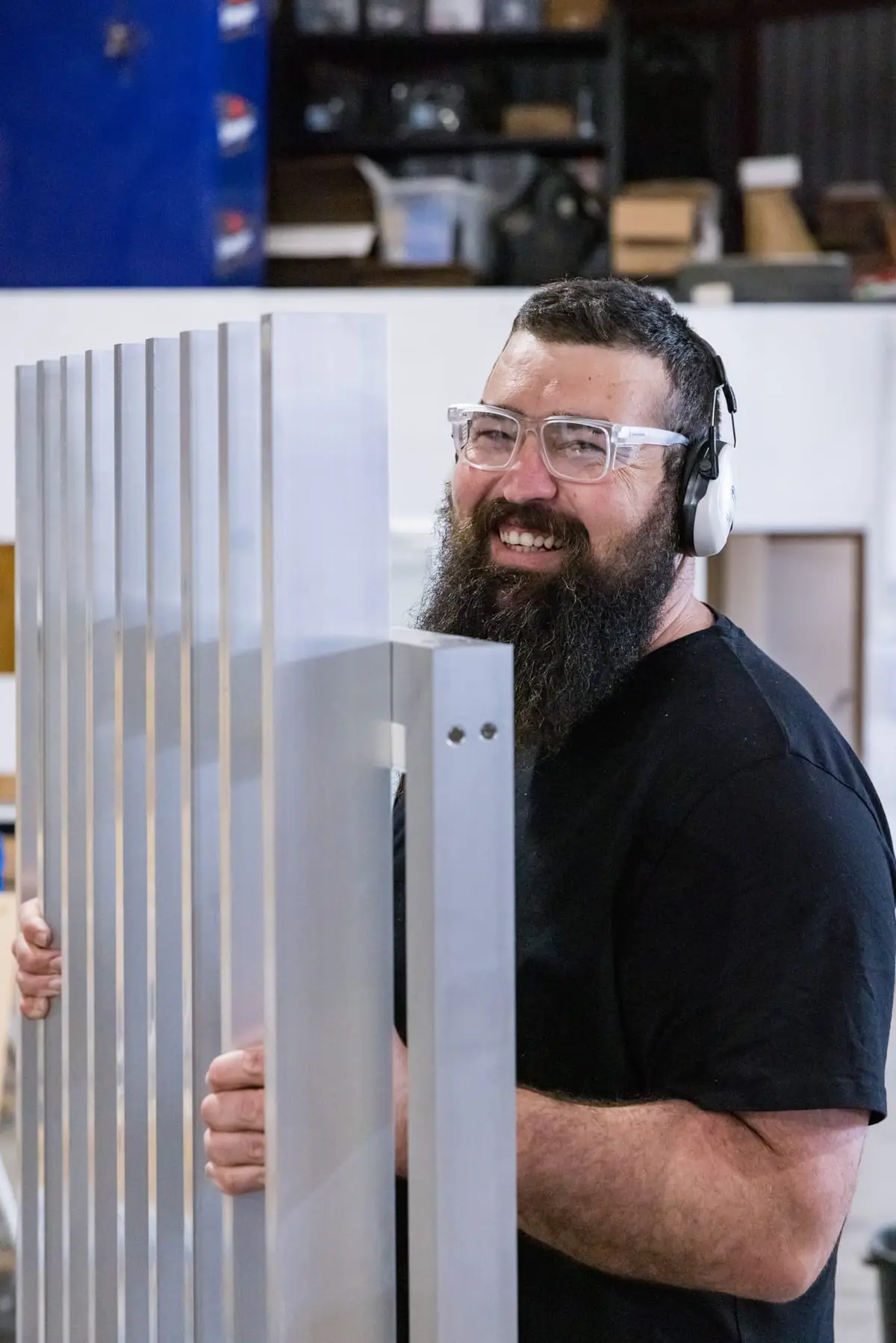 A fabricator carrying a freshly machined TrueBatten panel through the Landsdale workshop